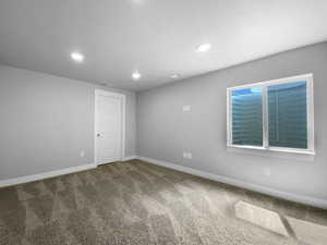 Empty room with carpet floors, baseboards, recessed lighting, and visible vents