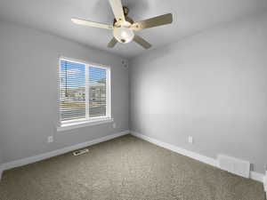 Spare room featuring visible vents, baseboards, a ceiling fan, and carpet floors