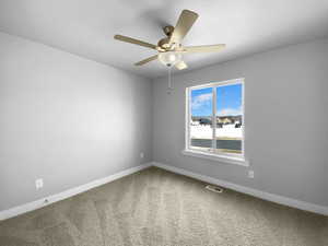 Carpeted empty room featuring visible vents, baseboards, and a ceiling fan