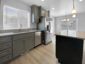 Kitchen with gray cabinetry, visible vents, stainless steel appliances, light wood finished floors, and a sink