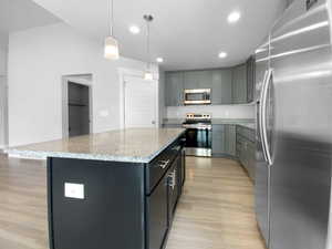 Kitchen with light wood-type flooring, a kitchen island, recessed lighting, stainless steel appliances, and decorative light fixtures