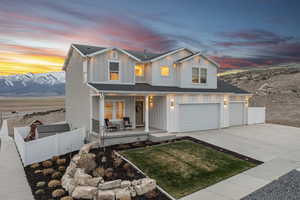Modern farmhouse with board and batten siding, a porch, fence, an attached garage, and driveway