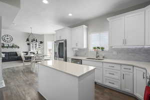 Kitchen with dark wood-type flooring, a sink, white cabinets, and stainless steel appliances