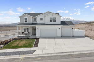 View of front facade featuring board and batten siding, covered porch, a garage, and fence