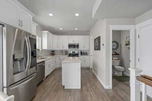 Kitchen with white cabinets, a sink, appliances with stainless steel finishes, dark wood finished floors, and backsplash