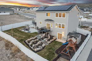Back of house featuring a patio area, a fenced backyard, a playground, and roof mounted solar panels