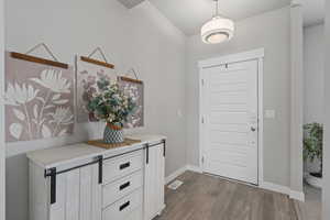Entrance foyer featuring visible vents, baseboards, and wood finished floors