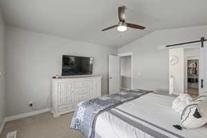 Bedroom with light colored carpet, visible vents, a barn door, lofted ceiling, and baseboards