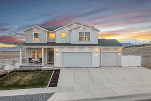 View of front of house featuring driveway, board and batten siding, fence, and covered porch