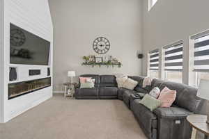 Living room featuring a towering ceiling, baseboards, and carpet floors