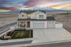 View of front of home with board and batten siding, a mountain view, a porch, fence, and driveway