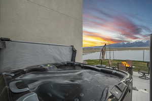 Exterior space featuring a mountain view, a patio area, a fenced backyard, an outdoor fire pit, and a hot tub