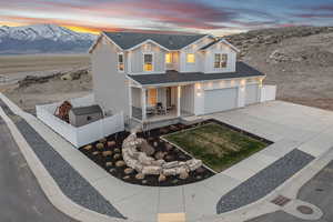 Modern farmhouse style home with a mountain view, driveway, board and batten siding, a porch, and fence