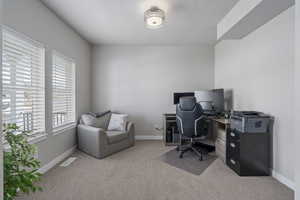 Office area featuring visible vents, baseboards, and light colored carpet