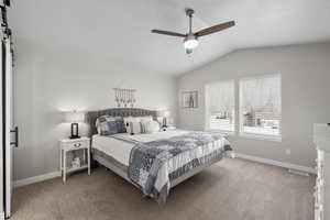 Carpeted bedroom featuring a barn door, visible vents, baseboards, and lofted ceiling