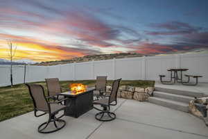 Patio terrace at dusk featuring a fire pit and a fenced backyard