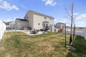 Rear view of house with a hot tub, a patio area, a fenced backyard, a playground, and stucco siding