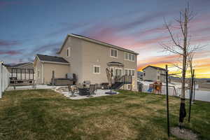 Back of property featuring a hot tub, a yard, a fenced backyard, a patio, and a playground