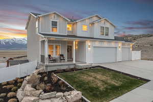 View of front of house featuring concrete driveway, board and batten siding, a porch, a garage, and fence