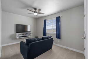 Carpeted living area featuring baseboards and a ceiling fan