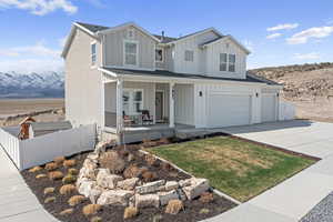 View of front of property with board and batten siding, a garage, a porch, fence, and driveway