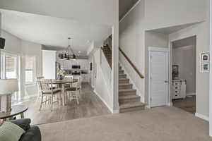 Dining space with baseboards, a chandelier, light carpet, stairway, and a high ceiling