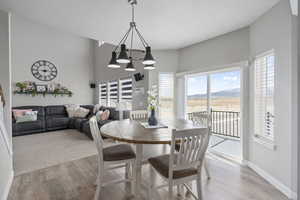 Dining area featuring a chandelier, light wood-style floors, baseboards, and a textured ceiling