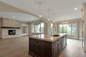 Kitchen with a sink, light countertops, a chandelier, light wood-style floors, and dark brown cabinets