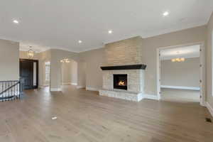 Unfurnished living room with a chandelier, crown molding, and light wood-style floors