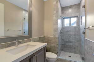 Full bath with toilet, tile walls, a shower stall, and vanity
