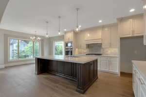 Kitchen with an inviting chandelier, a sink, light countertops, appliances with stainless steel finishes, and backsplash