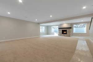 Unfurnished living room with baseboards, recessed lighting, light carpet, and a fireplace
