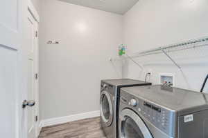 Laundry room with baseboards, laundry area, washing machine and clothes dryer, and wood finished floors
