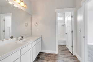 Bathroom featuring vanity, baseboards, shower / bathing tub combination, and wood finished floors