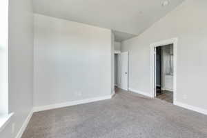 Unfurnished bedroom featuring baseboards, lofted ceiling, carpet, and ensuite bath