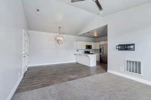 Unfurnished living room with visible vents, baseboards, dark wood-style floors, and ceiling fan with notable chandelier