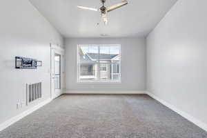 Empty room with carpet, visible vents, baseboards, and ceiling fan