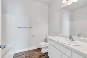 Full bath featuring toilet, wood finished floors, vanity, and baseboards