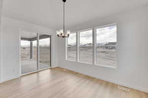 Unfurnished dining area with a wealth of natural light, visible vents, a chandelier, and wood finished floors