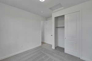Unfurnished bedroom featuring carpet flooring, baseboards, attic access, and a closet