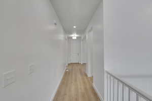 Corridor with light wood-type flooring and baseboards