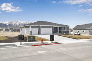 View of front of home featuring concrete driveway, stone siding, a mountain view, and an attached garage
