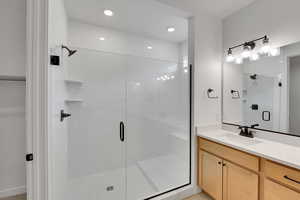 Bathroom featuring recessed lighting, vanity, and a stall shower