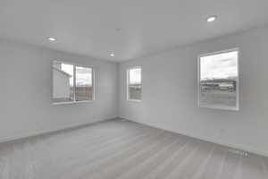 Empty room with light colored carpet, baseboards, visible vents, and recessed lighting