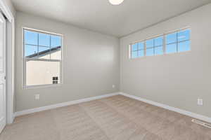 Carpeted spare room featuring visible vents, baseboards, and a healthy amount of sunlight