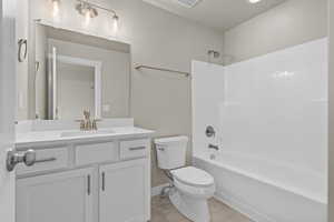Bathroom with visible vents, baseboards, toilet, vanity, and shower / bathtub combination