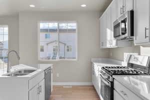 Kitchen featuring a healthy amount of sunlight, light wood-style floors, a sink, and appliances with stainless steel finishes