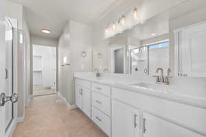 Bathroom with a shower stall, double vanity, a sink, and a spacious closet