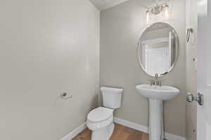 Half bath featuring baseboards, a sink, toilet, and wood finished floors