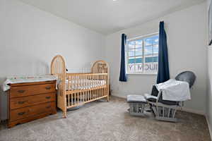 Carpeted bedroom with baseboards and a nursery area